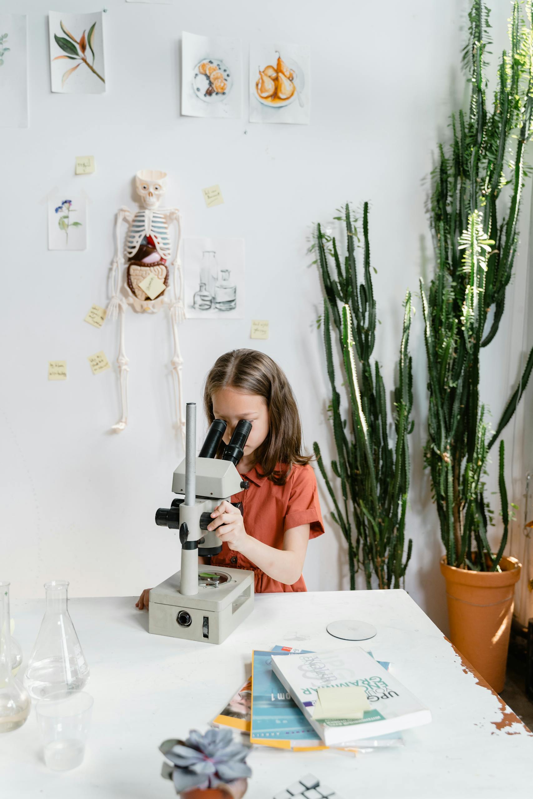 A young girl intently studies through a microscope in a science classroom, surrounded by educational materials.
