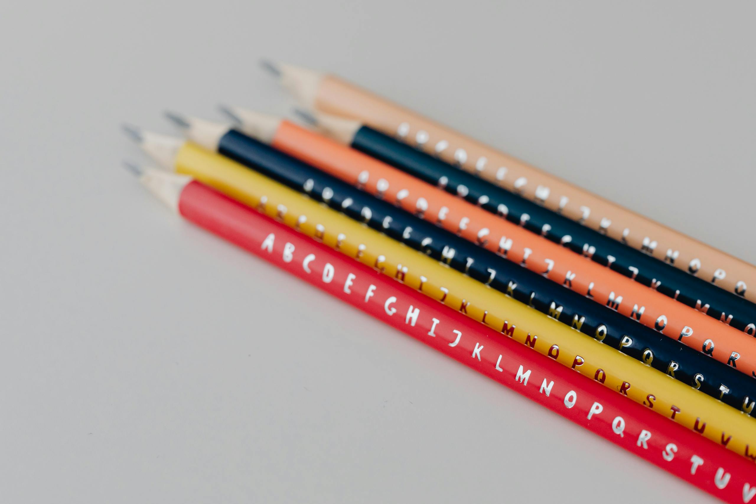 Colorful alphabet pencils neatly arranged on a gray background, ideal for educational themes.